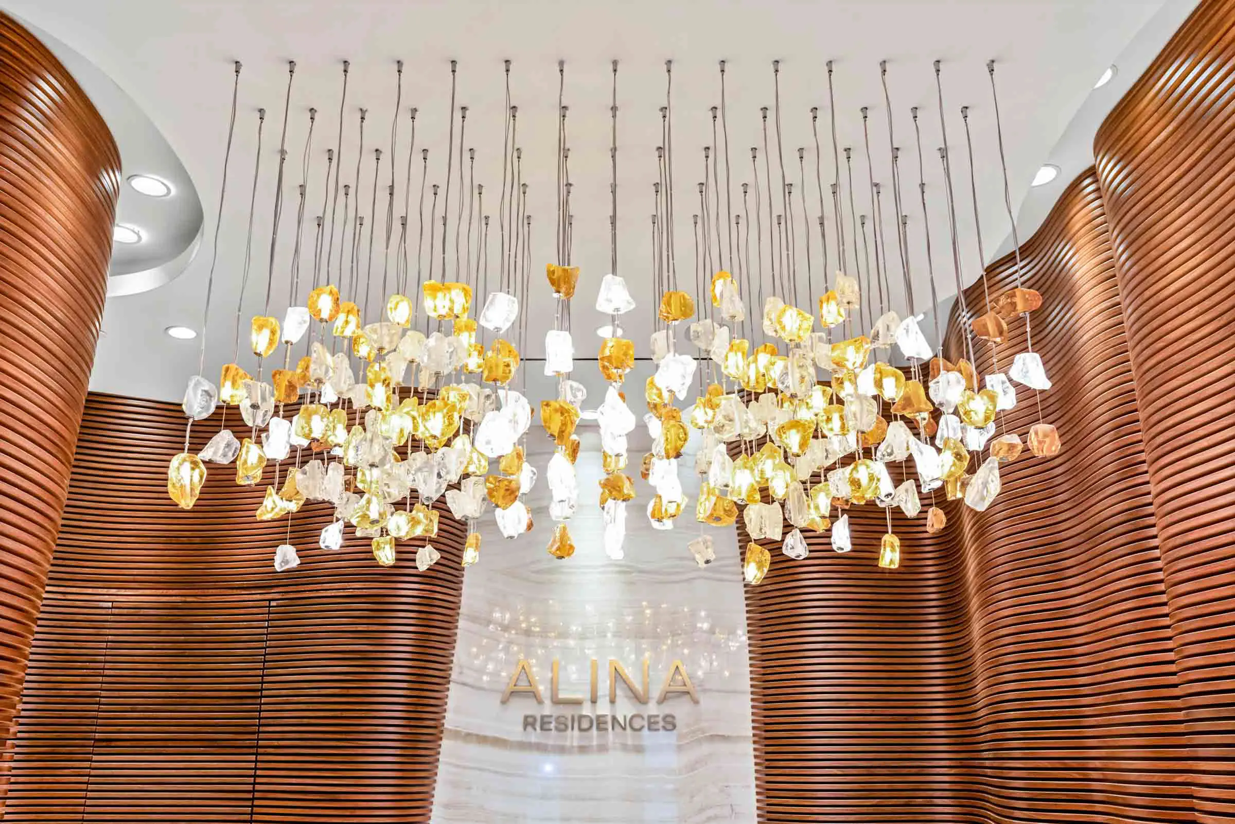 Elegant chandelier with white and yellow floral elements in a modern lobby.