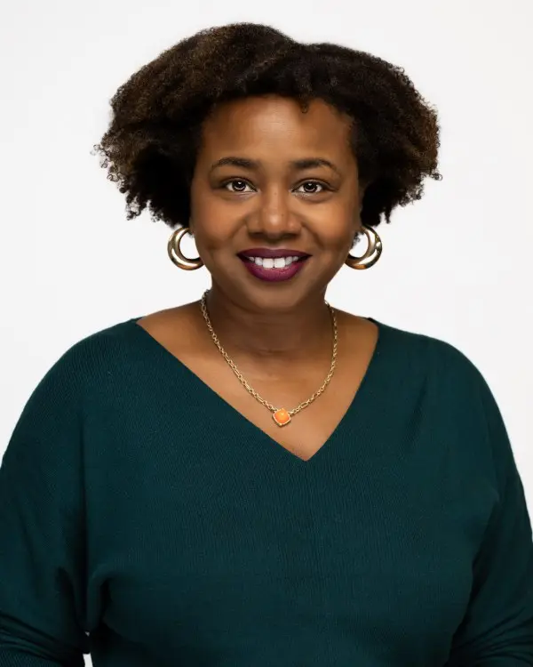 Smiling woman with natural hair in a green top against a white background.