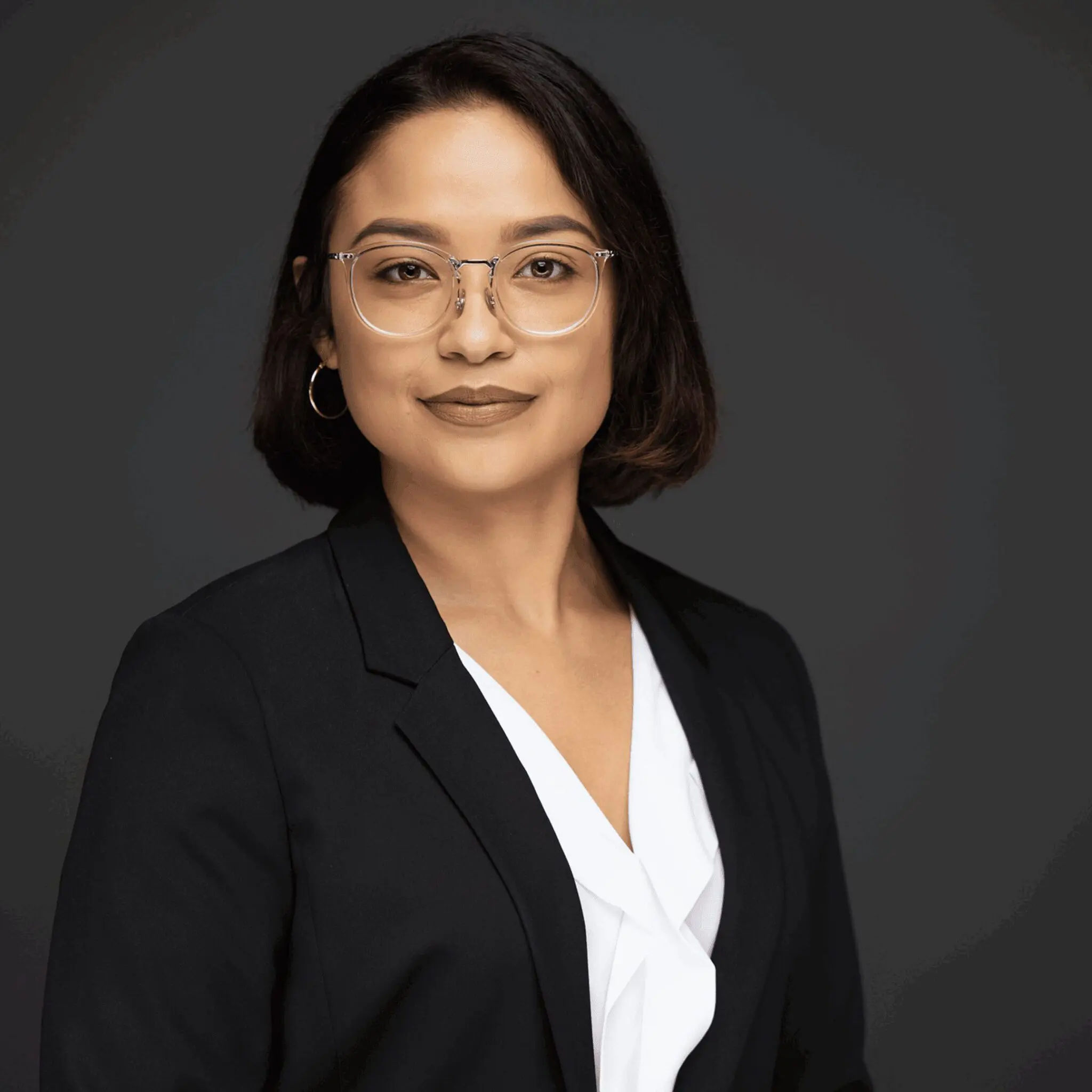 Professional woman in business attire with glasses and short hair.