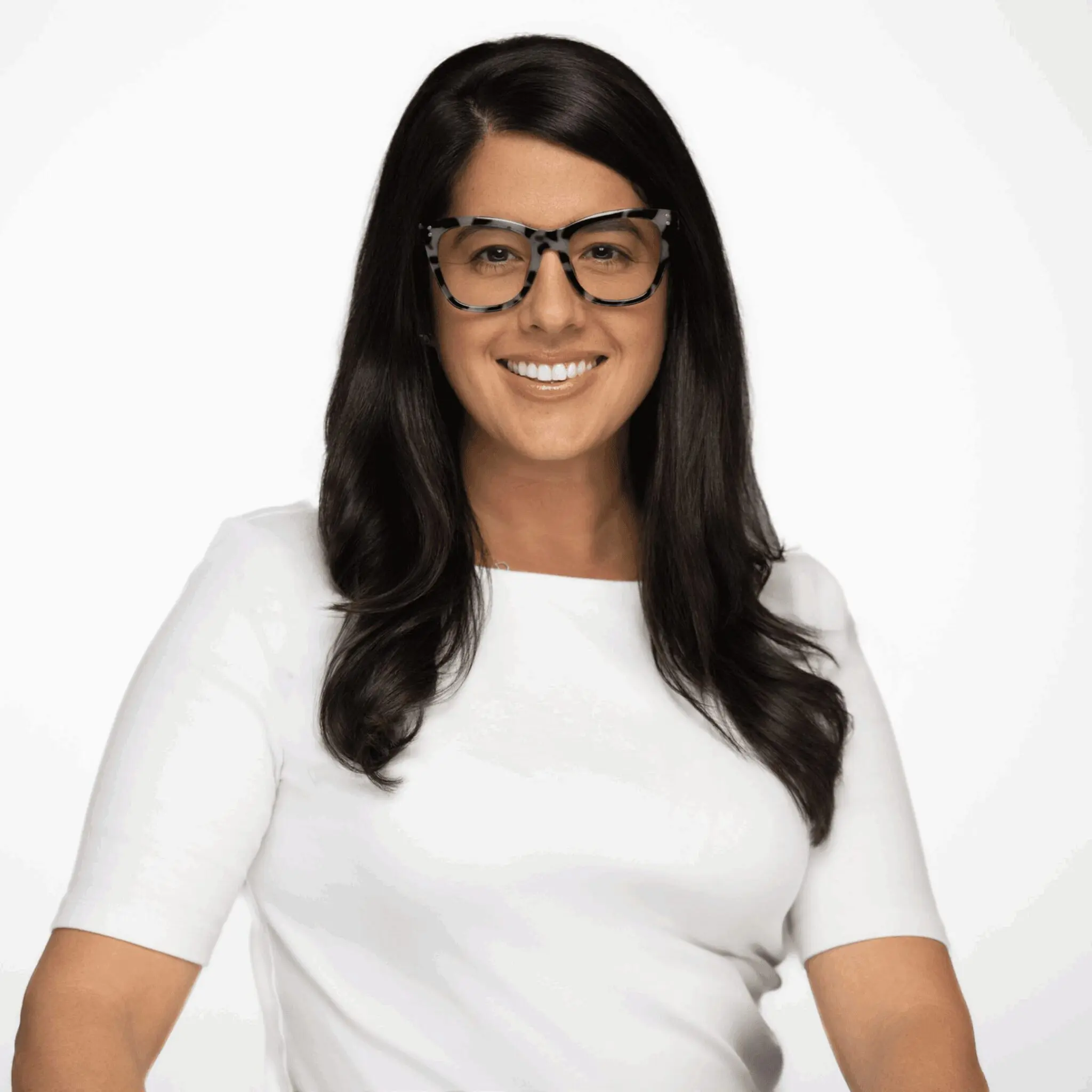 Woman in glasses smiling confidently in white shirt.
