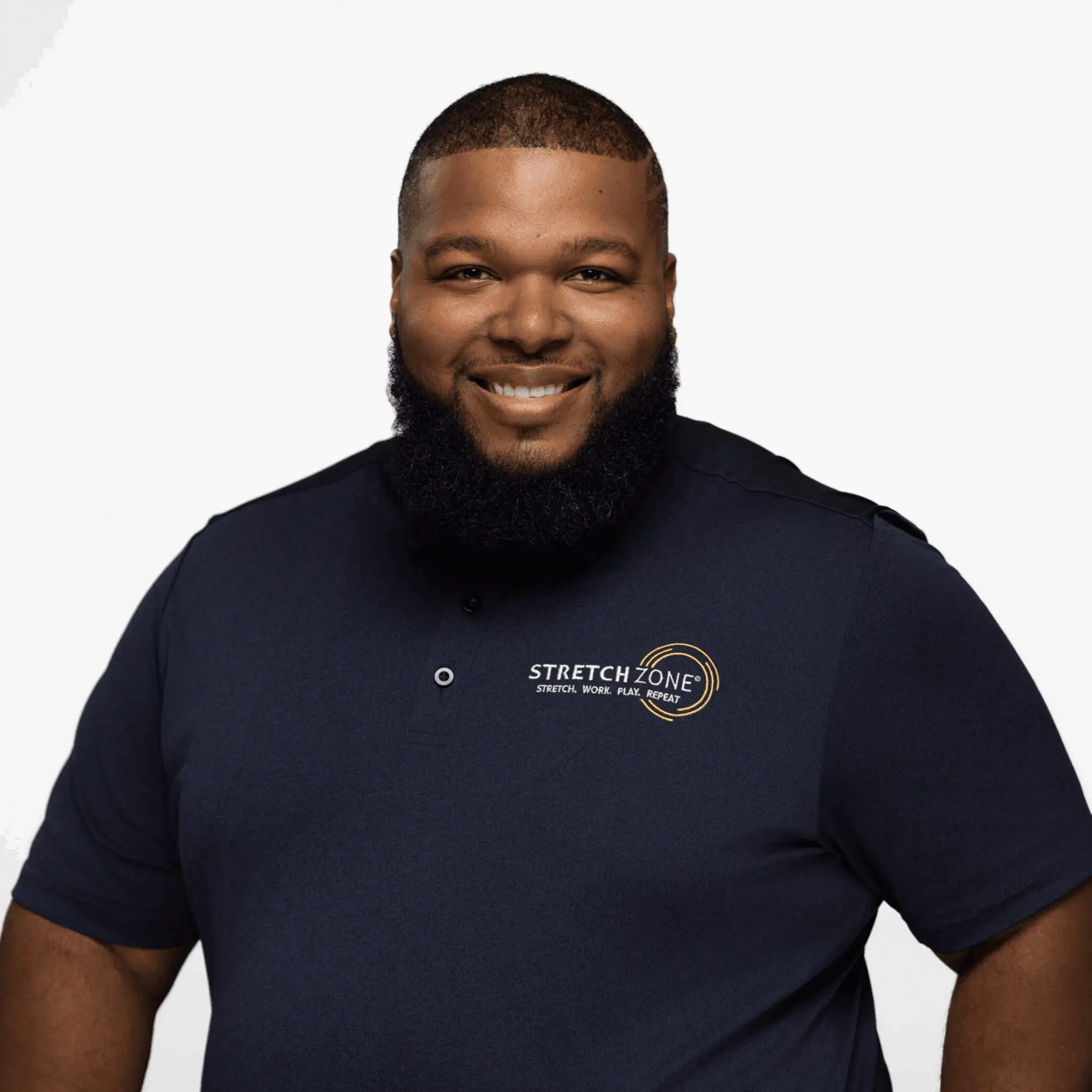 Smiling man wearing a navy blue polo shirt against a white background.