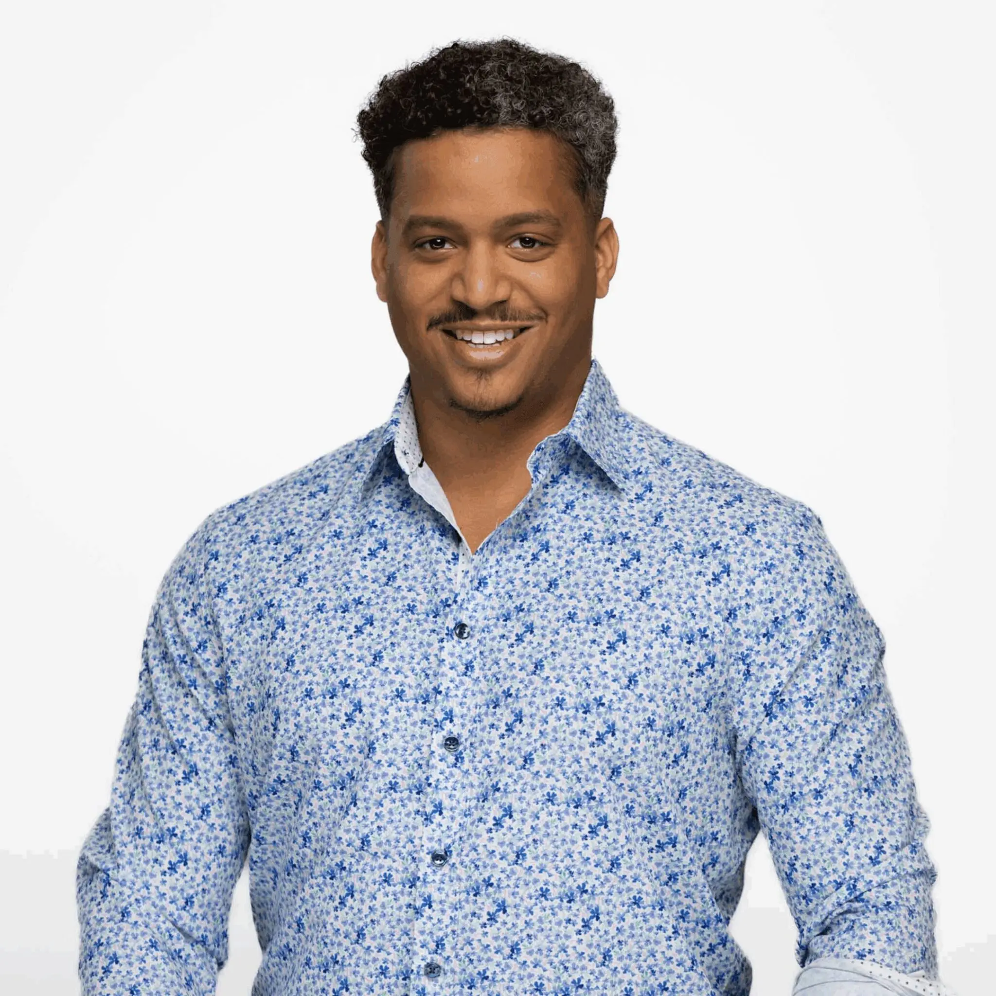 Smiling man wearing a blue floral shirt against a plain background.