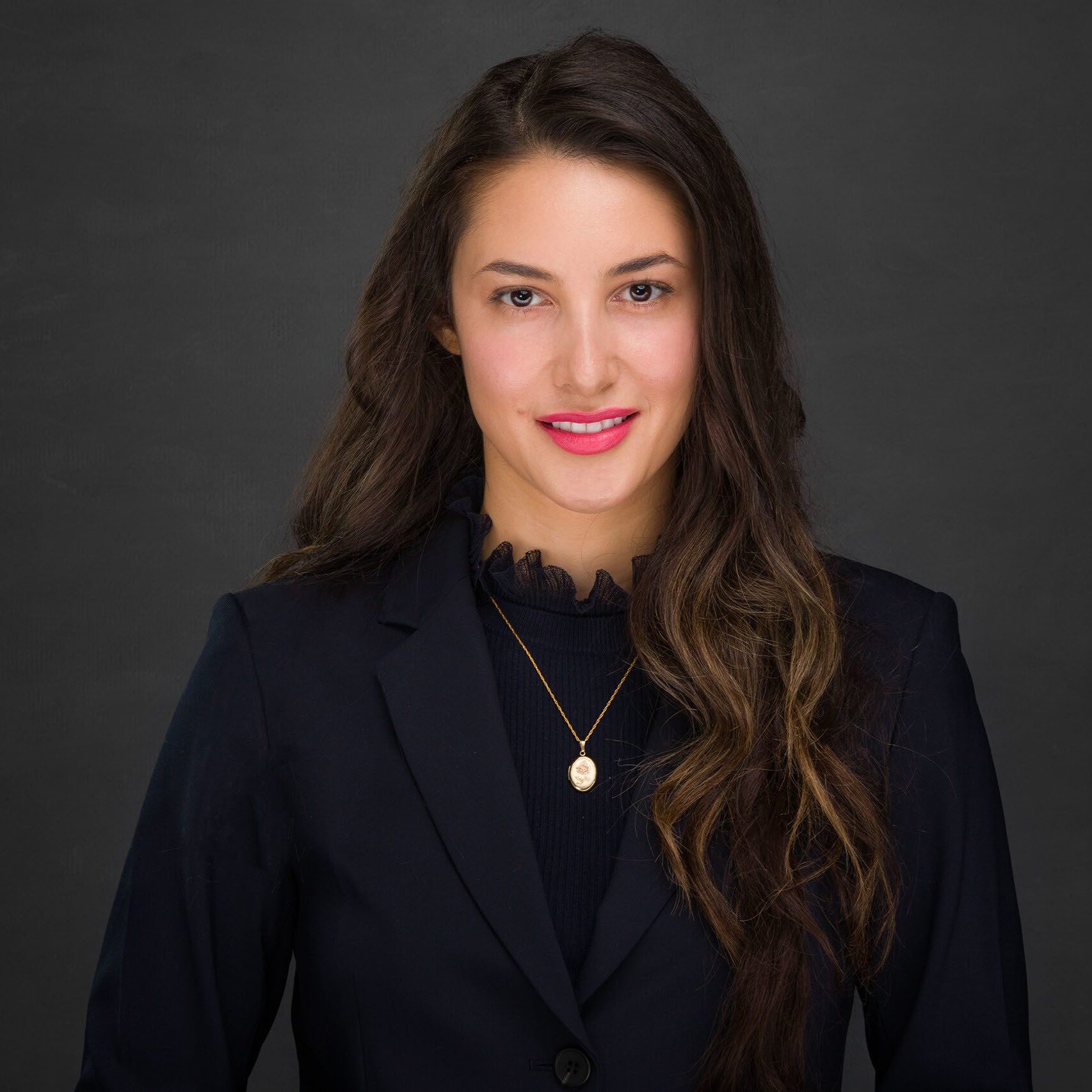 Professional headshot of a confident woman in a dark blazer.